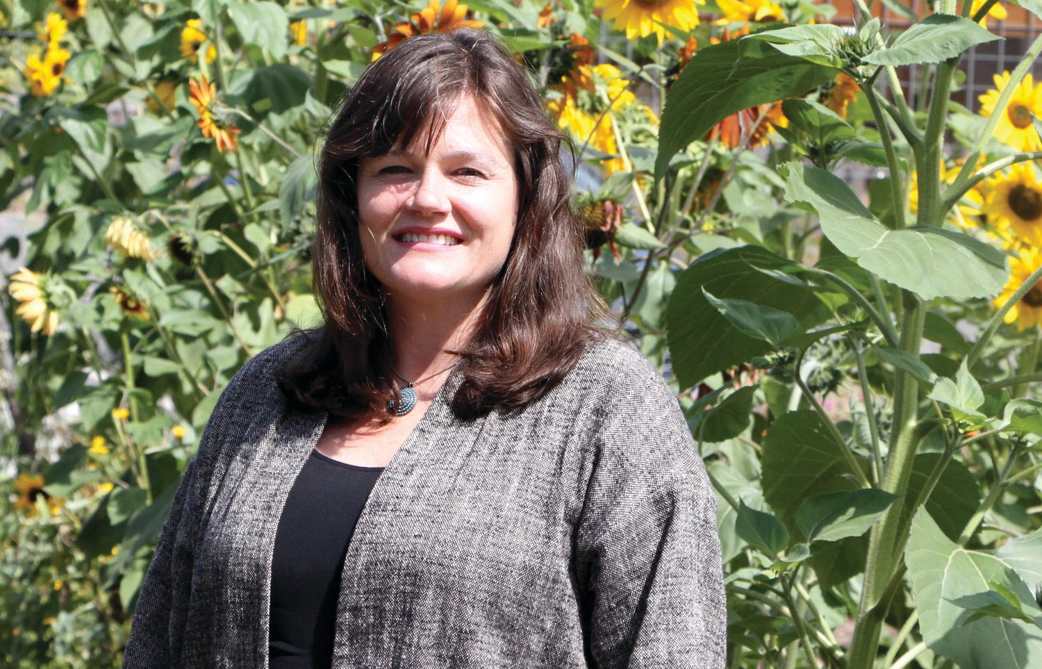 Rosenbury poses in front of the sunflowers at Salish Coast Elementary School’s teaching garden, an integral setting for her place-based learning program.