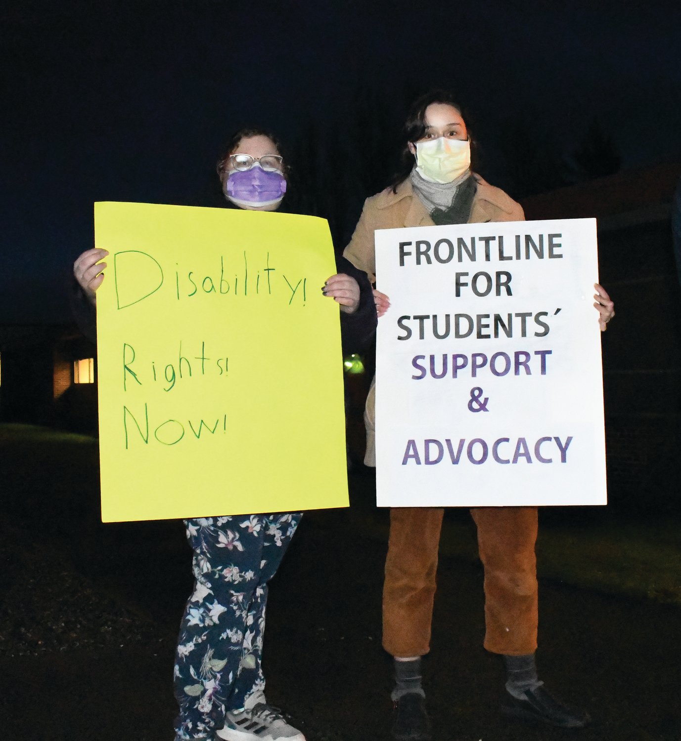 Laura Cornell (right) and another demonstrator hold signs in support of the Service Employees International Union Local 925 protest Thursday evening.