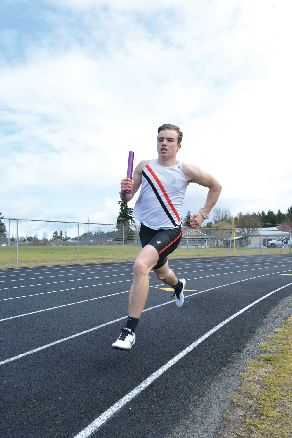 Rivals junior Austen Hammer dashes across the track field with the baton during a relay event at the Rainier Icebreaker Invitational meet.