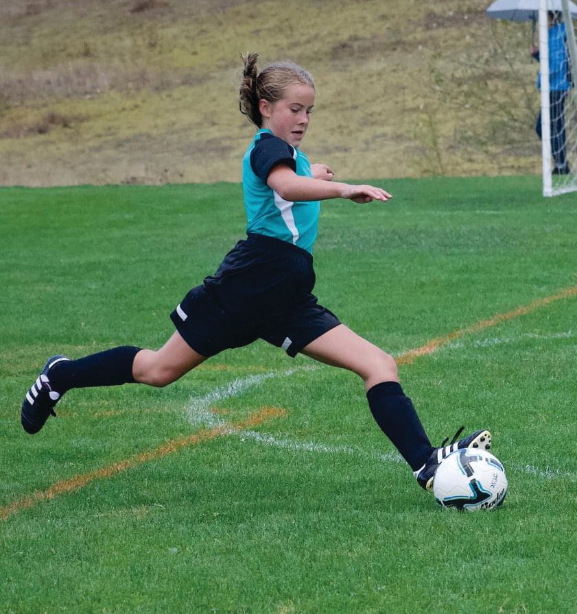 Youth soccer player Olivia McClemans winds up for a shot.
