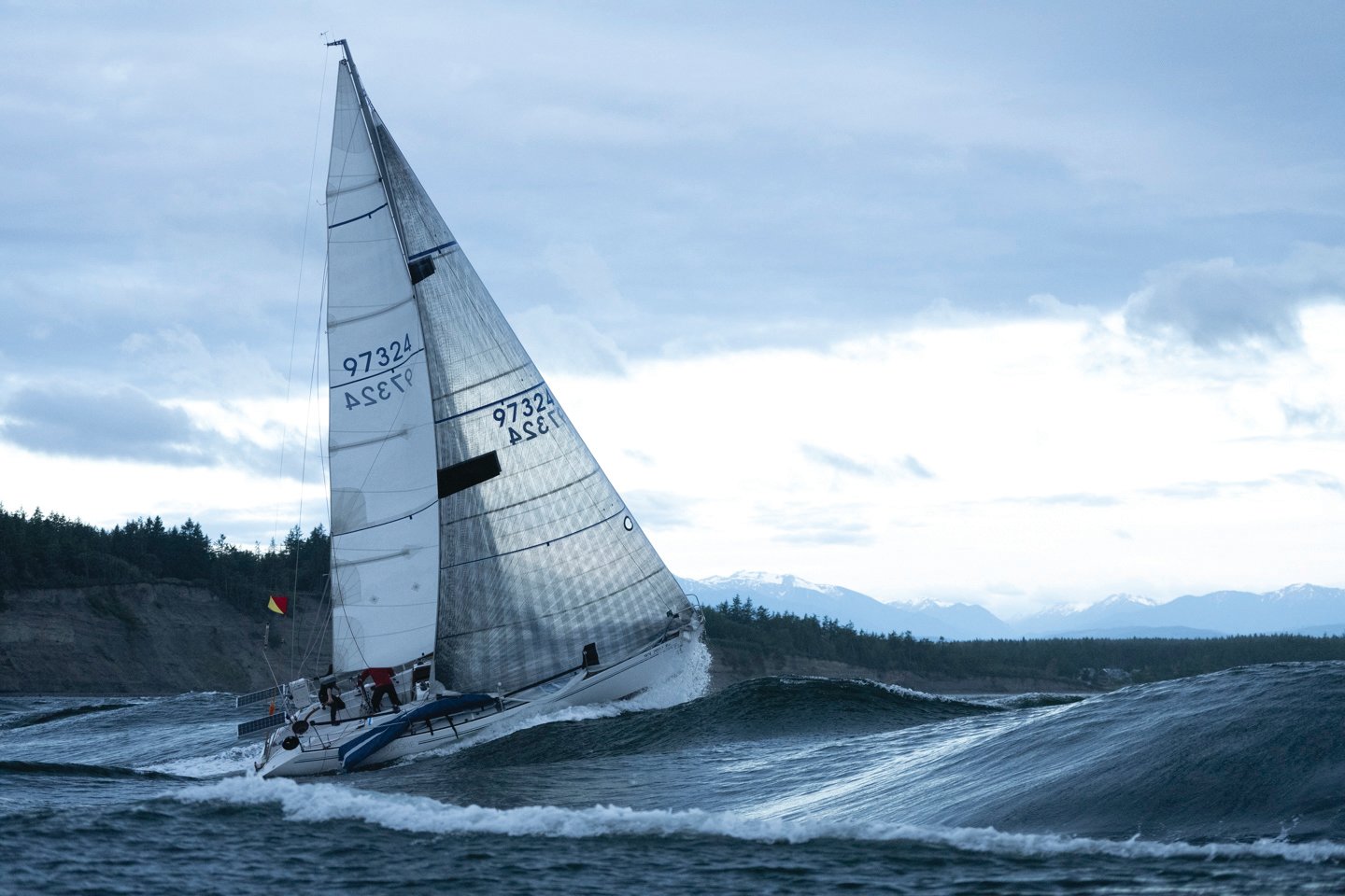 The monohull sailboat of Team Elsewhere pushes past a large wave in the Race to Alaska. The team ended in second place to win a set of steak knives.