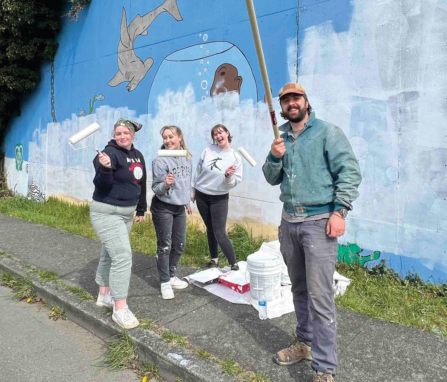 Charolette Falge, Emma Kane, Sidda Hayes, and Nick Mann pose while adding a new coat of paint to the 222-foot mural wall