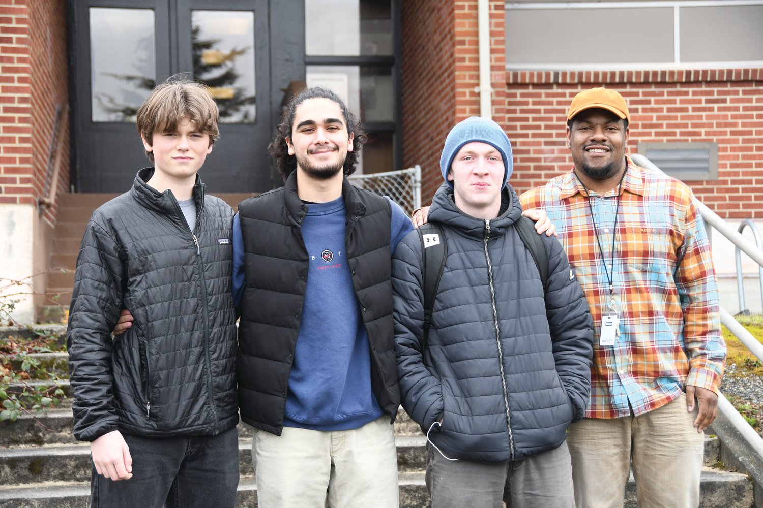 Port Townsend seniors Michael Petta, Lorenzo McCleese, Toby Fulton, and school wellness director Darrell Thomas pose outside the Gael Stuart Building on the Port Townsend High School campus.
