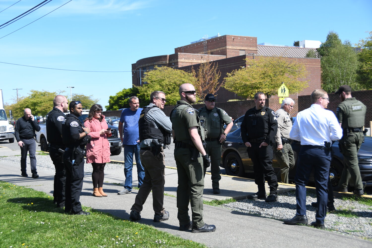 Law enforcement members with the Washington State Patrol, Port Townsend Police Department, and Jefferson County Sheriff's Office stand with Port Townsend School District officials outside Port Townsend High School prior to lifting the lockdown.